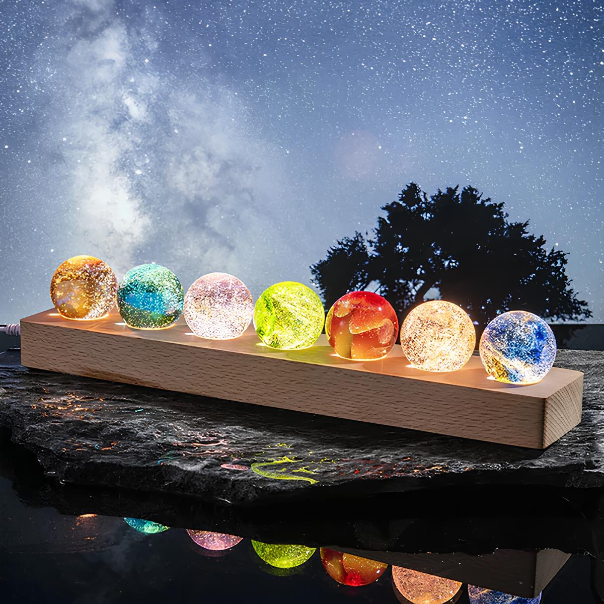 Set aus 7 leuchtenden Kristallkugeln mit Galaxie-Motiven auf Holzsockel