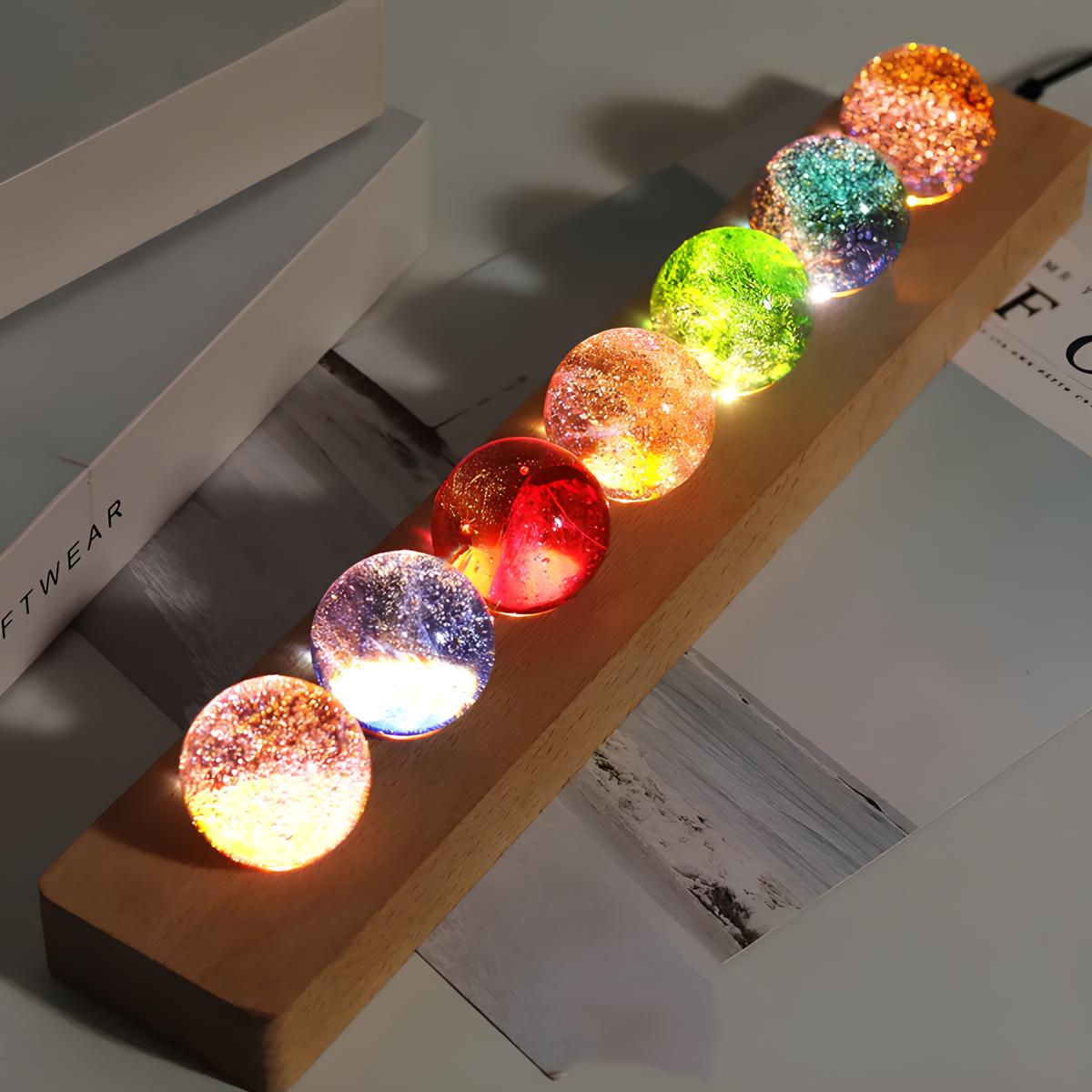 Set aus 7 leuchtenden Kristallkugeln mit Galaxie-Motiven auf Holzsockel