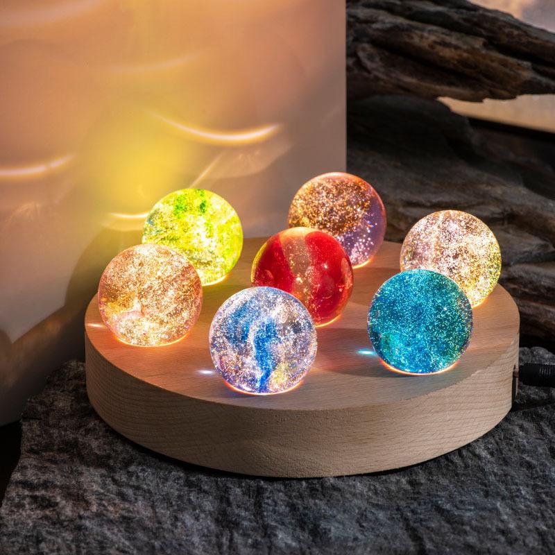 Set aus 7 leuchtenden Kristallkugeln mit Galaxie-Motiven auf Holzsockel