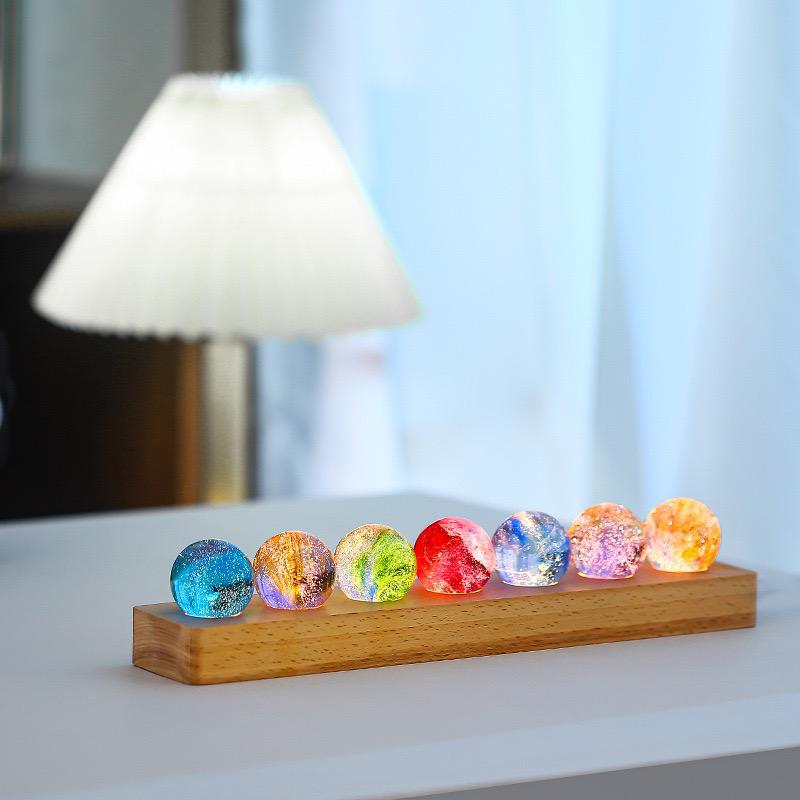 Set aus 7 leuchtenden Kristallkugeln mit Galaxie-Motiven auf Holzsockel
