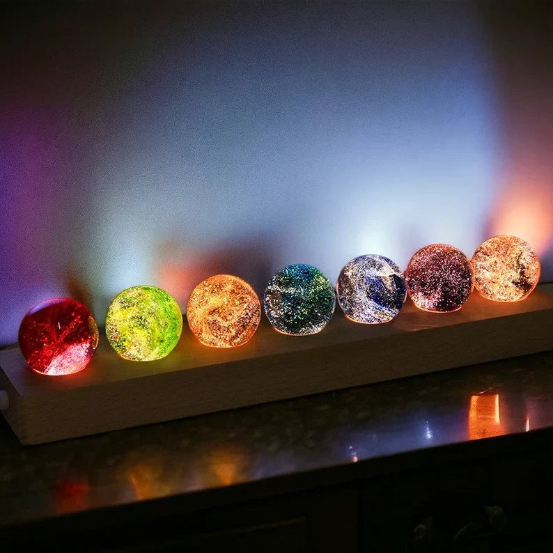 Set aus 7 leuchtenden Kristallkugeln mit Galaxie-Motiven auf Holzsockel