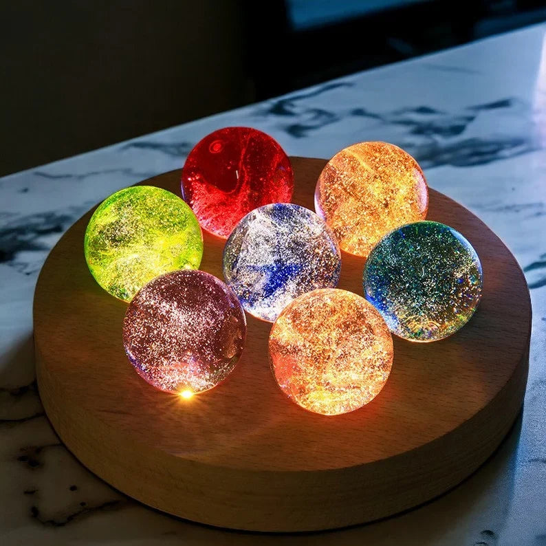 Set aus 7 leuchtenden Kristallkugeln mit Galaxie-Motiven auf Holzsockel